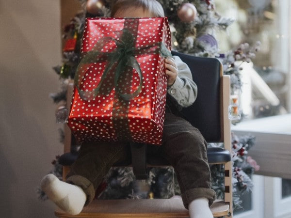 baby in Abiie high chair holding a wrapped present