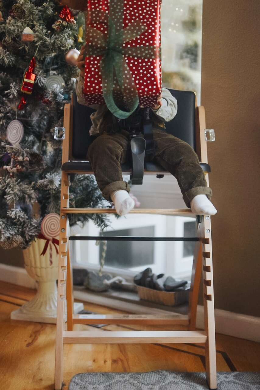 Child holding present in high chair