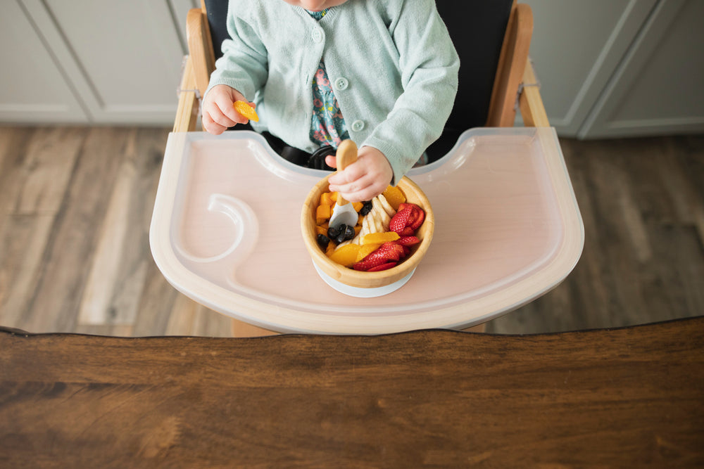 child eating fruit from bowl